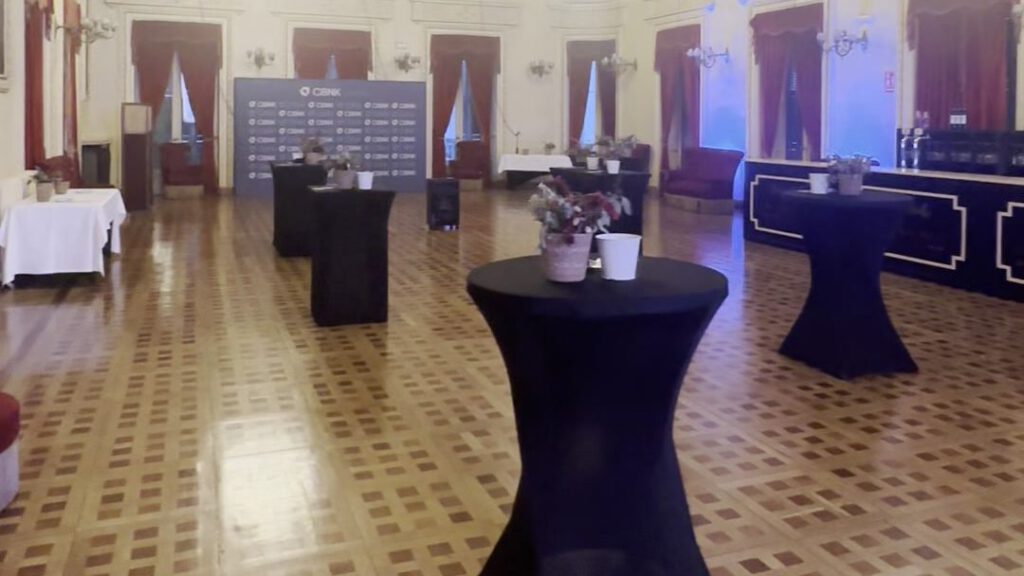 Salón del evento de CBNK con mesas de cóctel y photocall al fondo, producción de Atresmarketing
