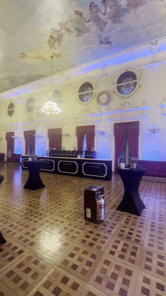 Salón histórico con iluminación ambiental y mesas de cóctel preparado para el evento de CBNK